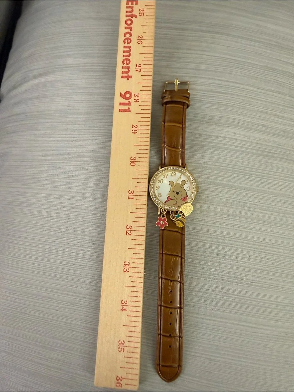 Disney Winnie the Pooh watch features a crystal-bezel dial and dangling charms o